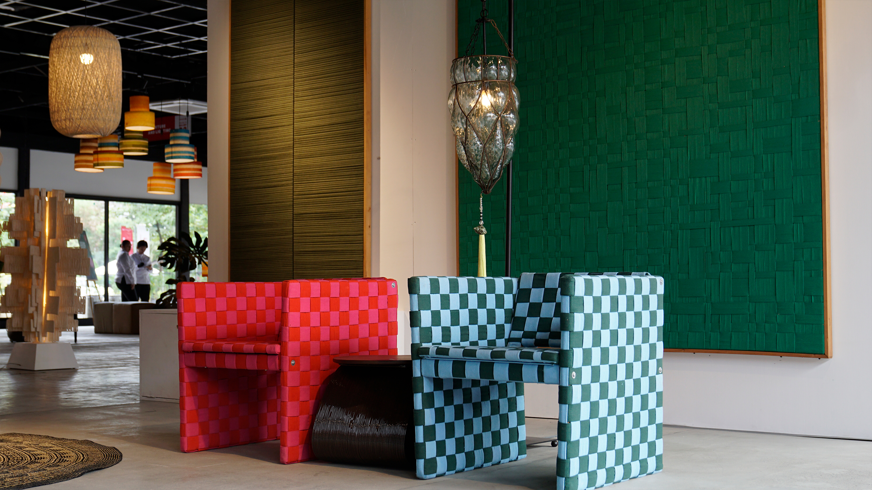 Red and blue checkered woven armchairs with a green wall panel behind them.
