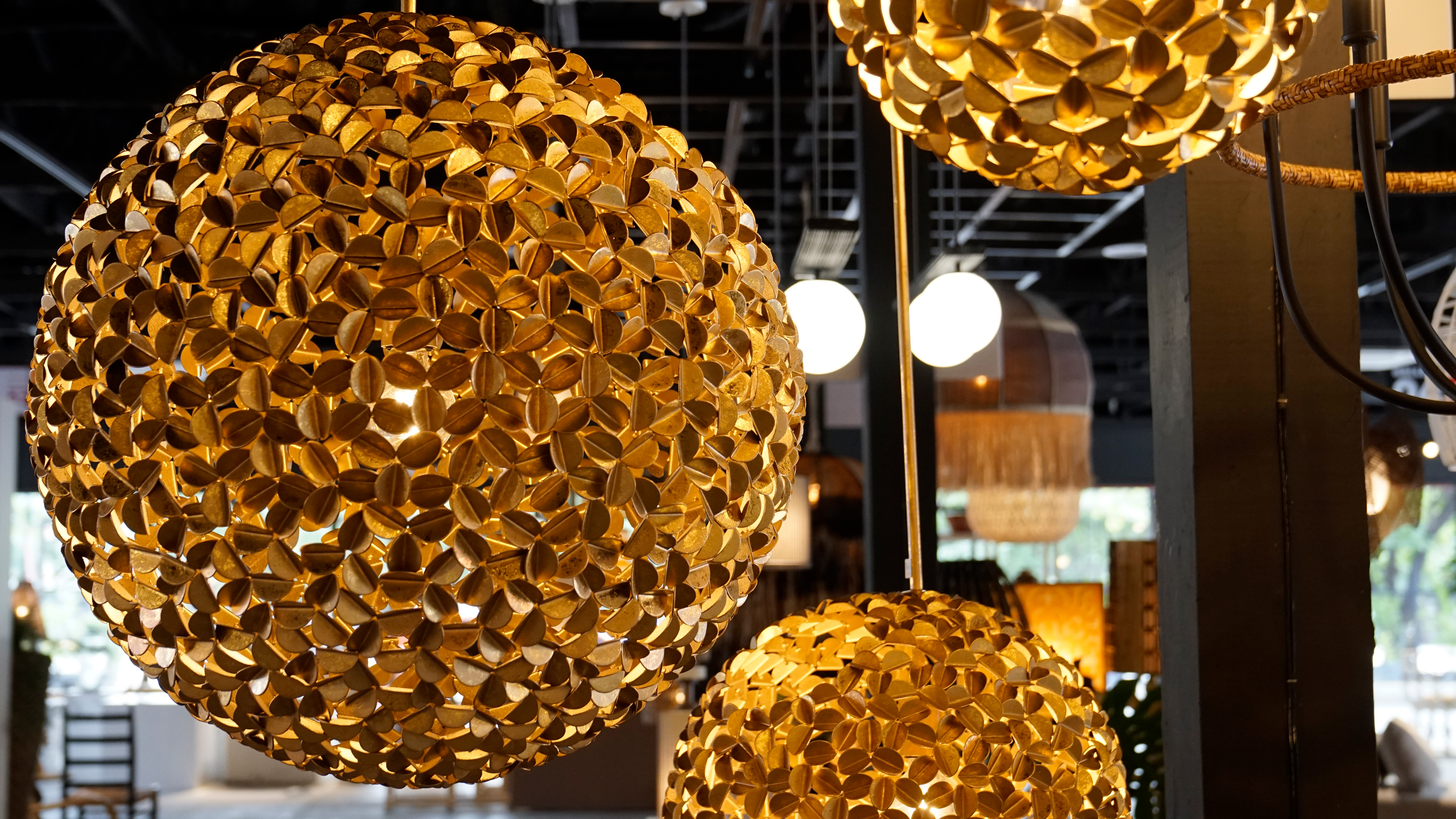 Golden spherical pendant lights made of small metal floral cutouts.