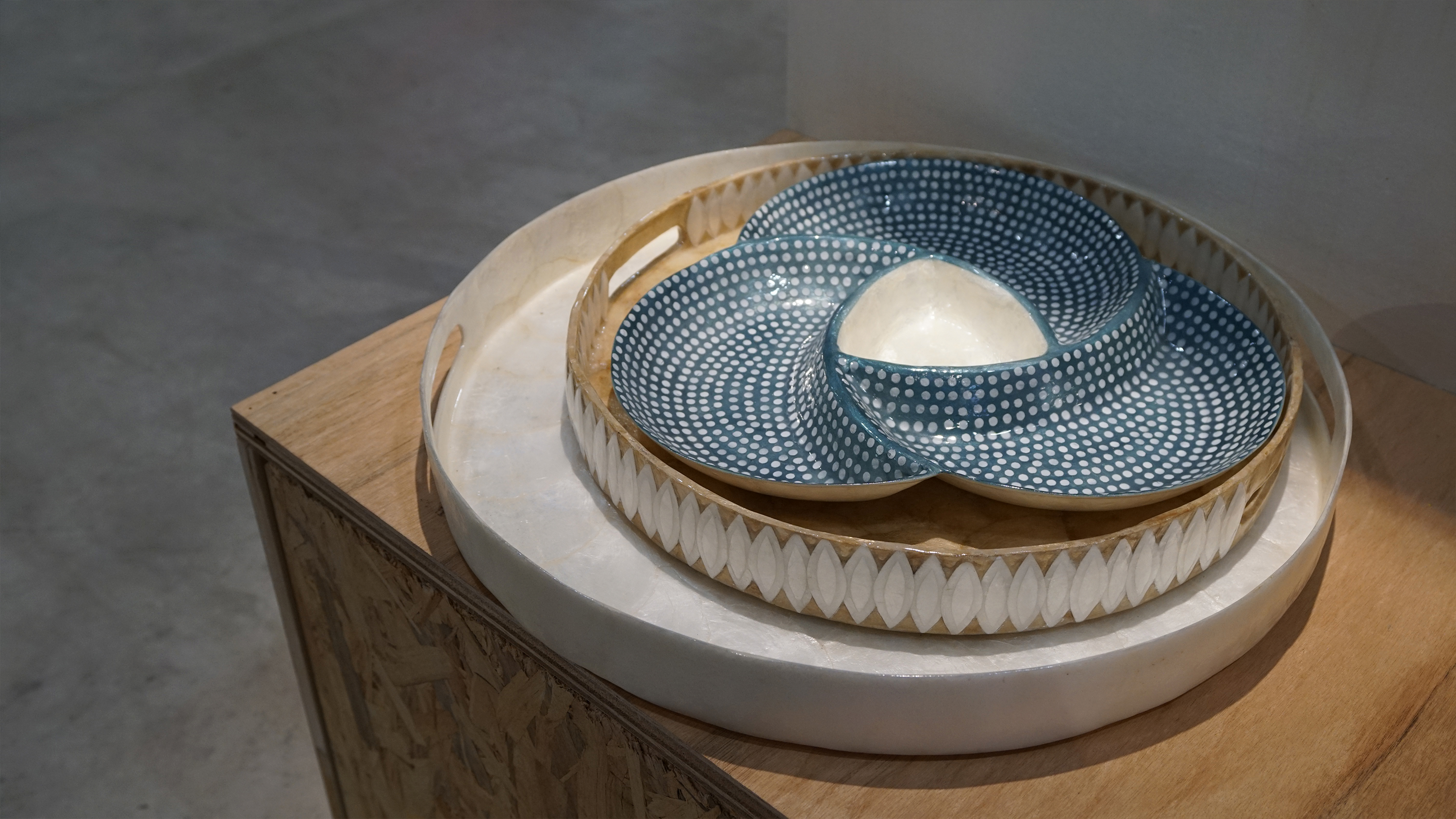 Stacked round serving trays, including a blue one with white dots and a cream one with a leaf-patterned rim.