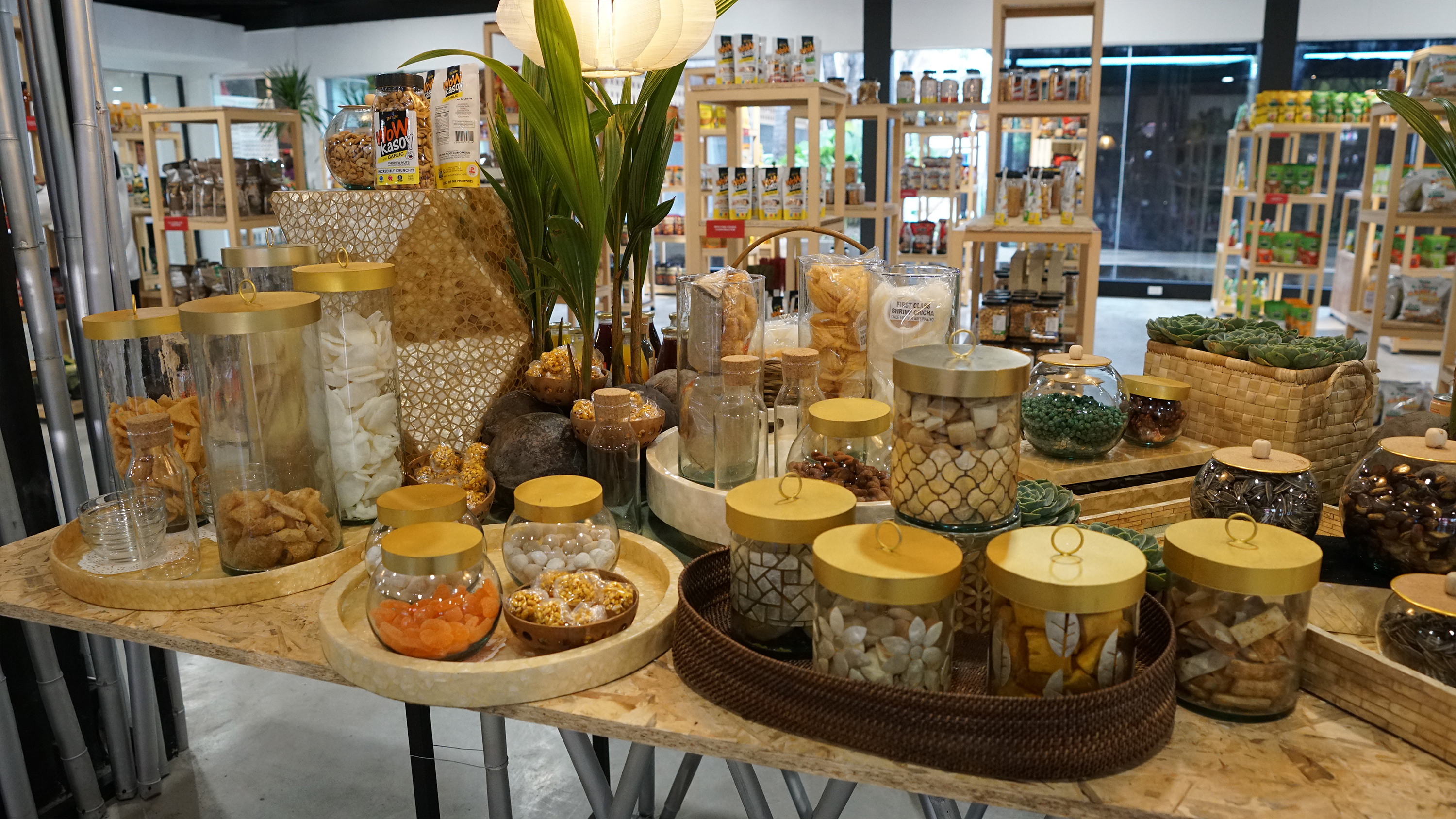 Glass jars filled with dried fruits, nuts, and chips arranged on a wooden table.